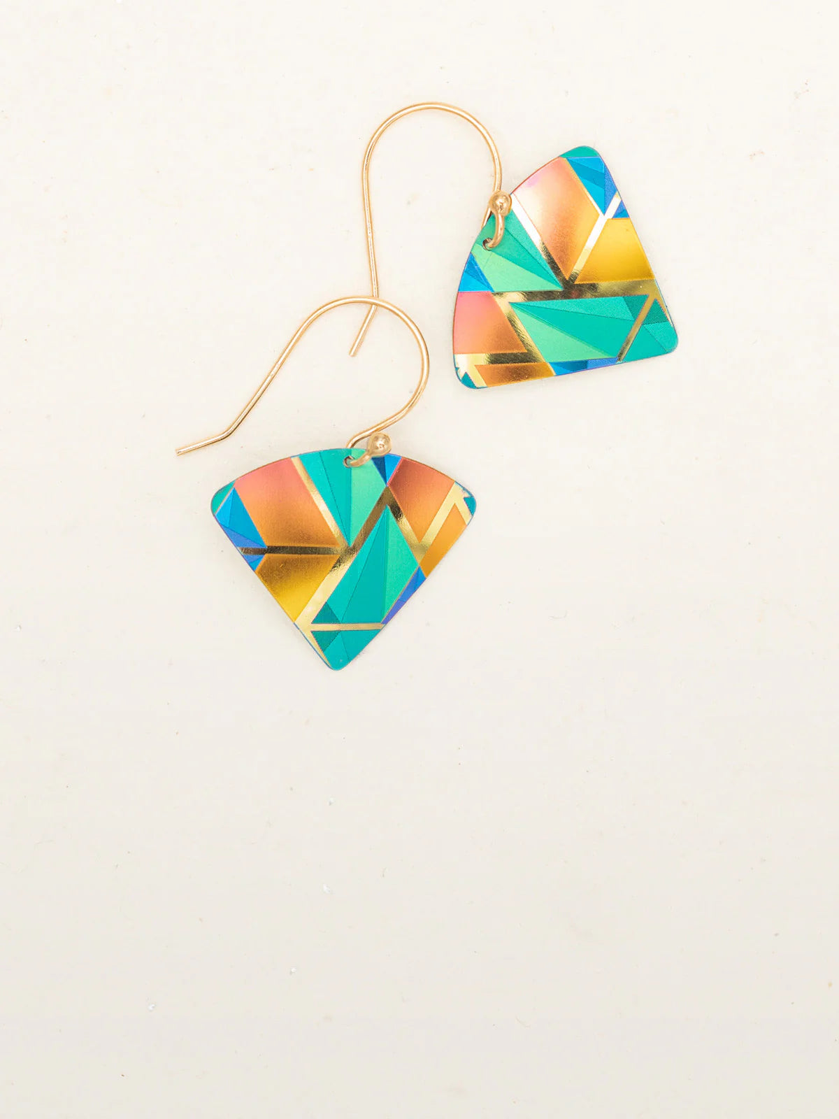 A pair of Holly Yashi Mercury Earrings, featuring a striking geometric pattern in hues of teal, blue, indigo, pink, and gold on a plain white background. The triangular, multicolored earrings are attached to gold-colored hooks.