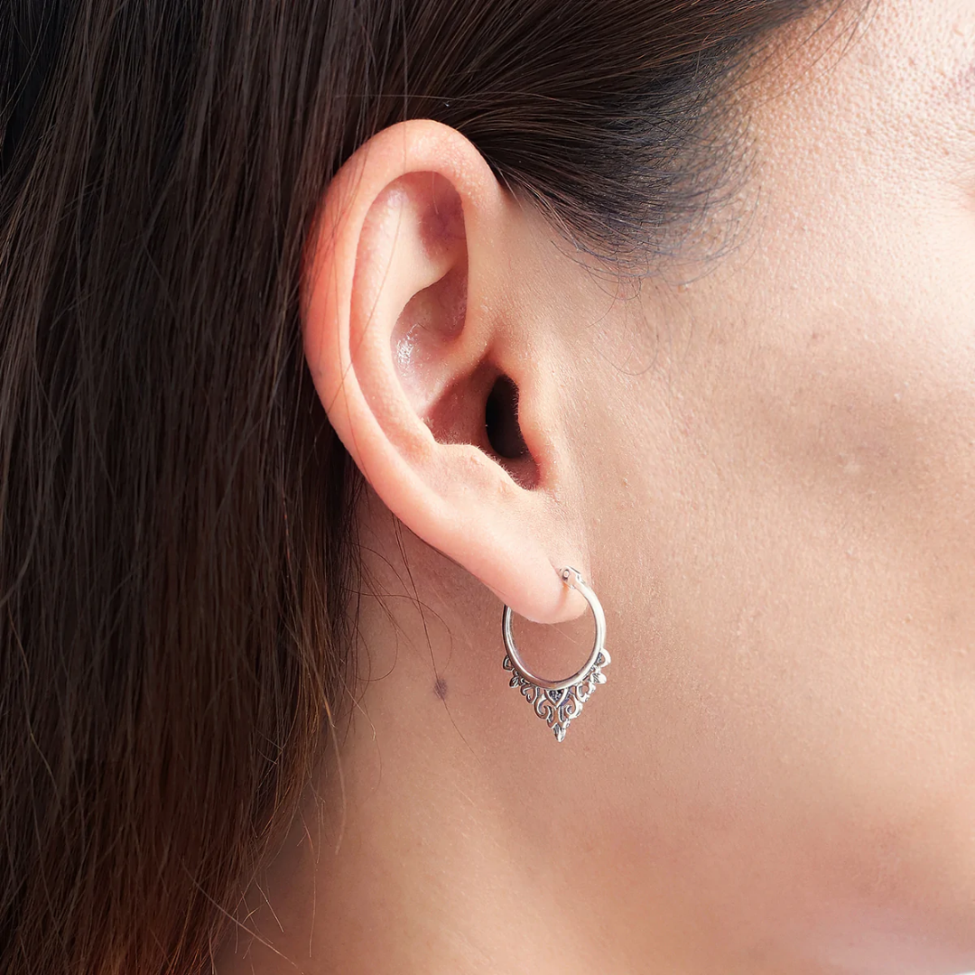 Snap top hoop with filigreed hearts border on the bottom. Seen on human ear from the side view.