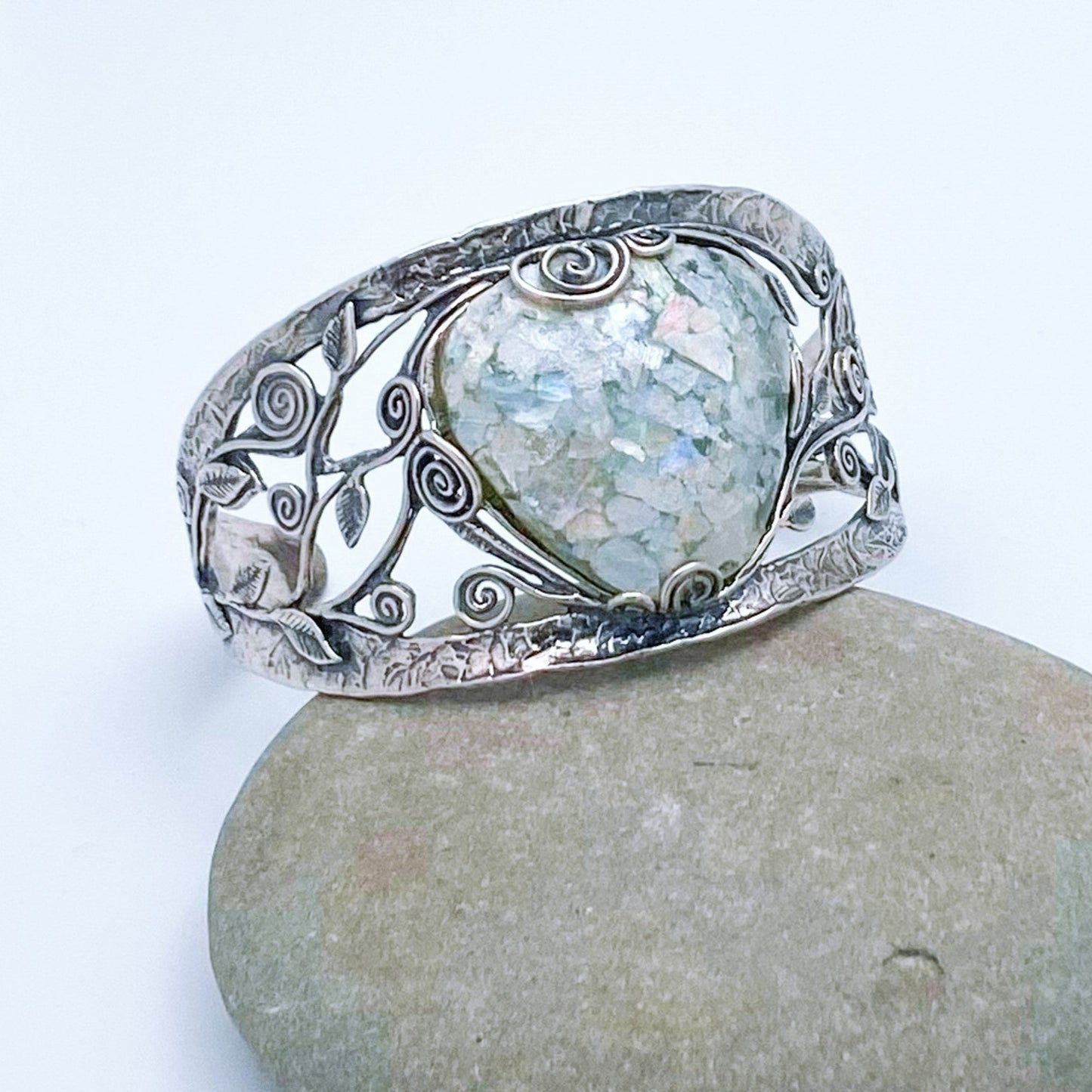 Large triangle shaped piece of Roman Glass set in a 925 Sterling Silver cuff bracelet - The band is adorned with vines and leaves and has a unique hammered appearance.