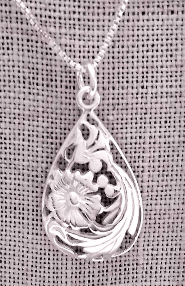 Domed teardrop shaped pendant with cutouts to show image of flowers and leaves