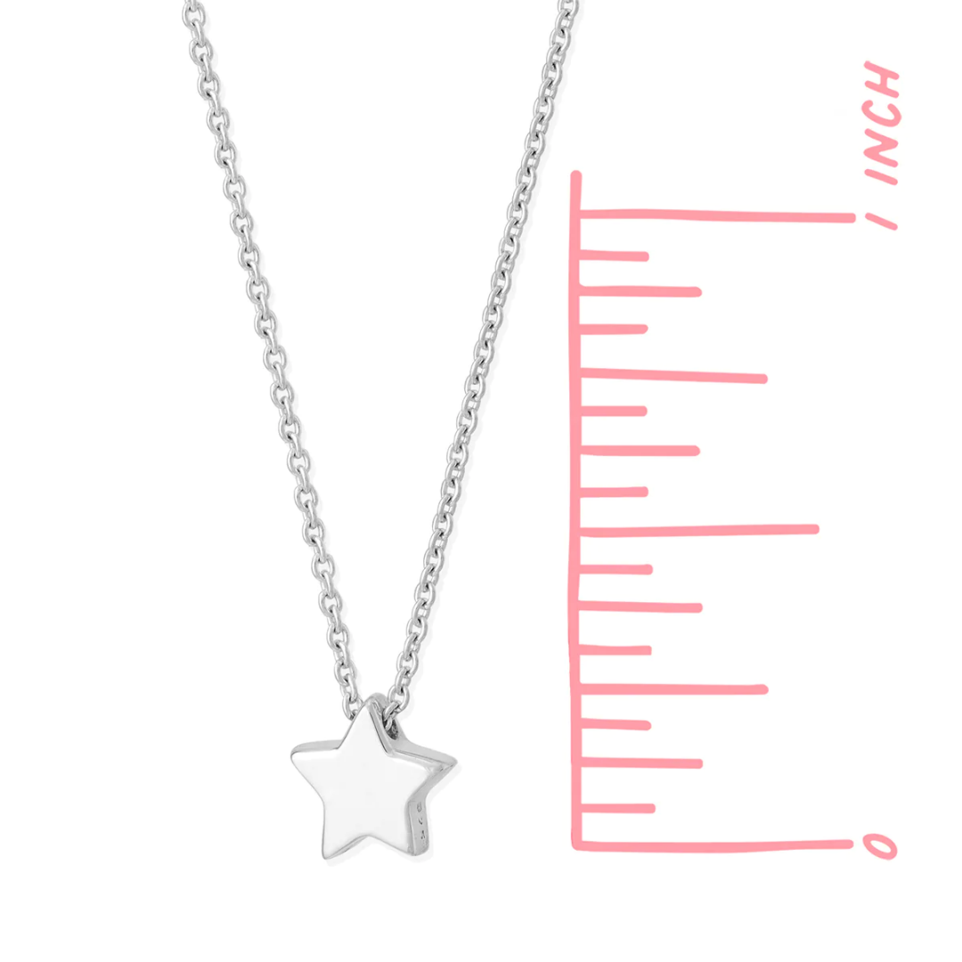 Small silver star pendant on delicate silver chain, seen on white background next to pink ruler, star pendant measures about .25 inches.