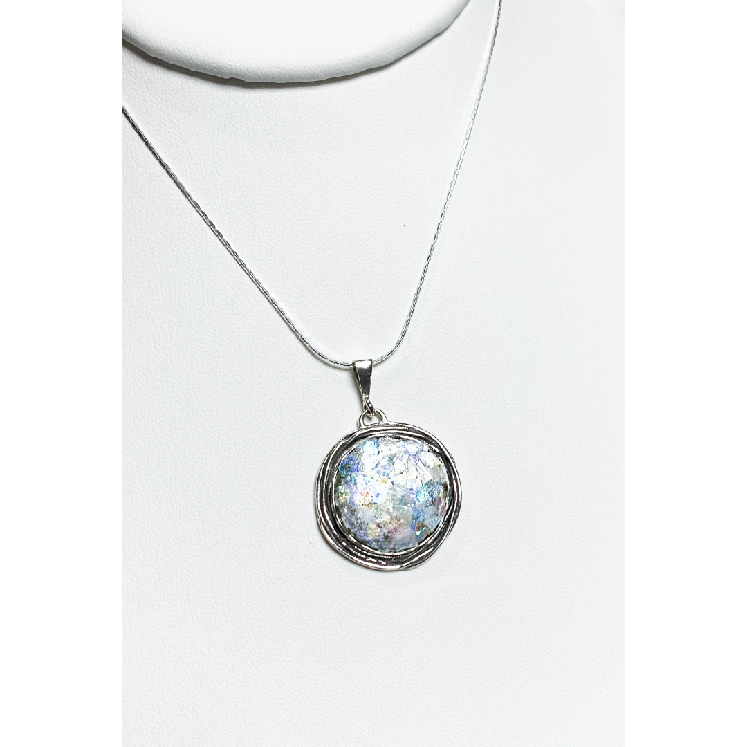 1 inch diameter piece of 2000 year old Roman glass set in an ornate Sterling Silver Bezel. Includes 18 inch chain.