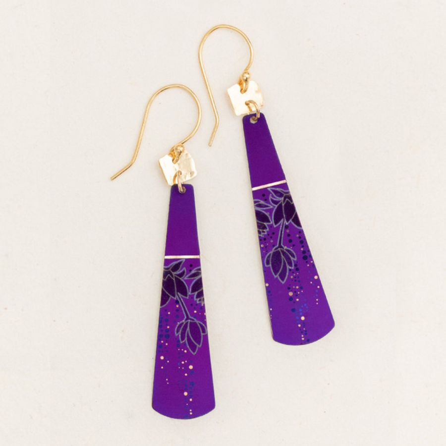 The Holly Yashi Tula Earrings are a pair of long, tapered earrings with gold hooks. These earrings feature a deep purple hue adorned with a delicate, floral design and small, colorful dots. Reminiscent of a romantic look, the intricate mix of lines and dots in various shades adds an elegant touch.