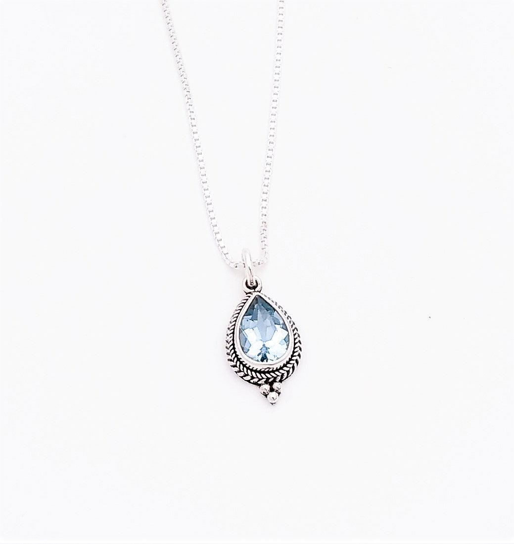 Sterling silver teardrop-shaped pendant with a blue topaz stone in the middle. Surrounding it is a bali rope design with three metal balls at the bottom. Comes on an 18-inch chain, December birthstone