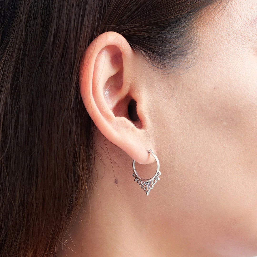 Snap top hoop with filigreed hearts border on the bottom. Seen on human ear from the side view. 