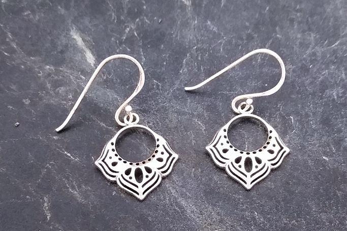 Boma Sterling Silver Dangle Earring on a large circular cut out bordered with three floral patterned designs at the bottom with cutouts. Earring is on a French wire.