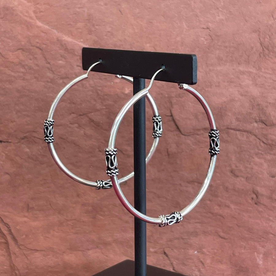 Sterling silver hoops earrings with a bali design at the left, right, and bottom part of the hoops.
