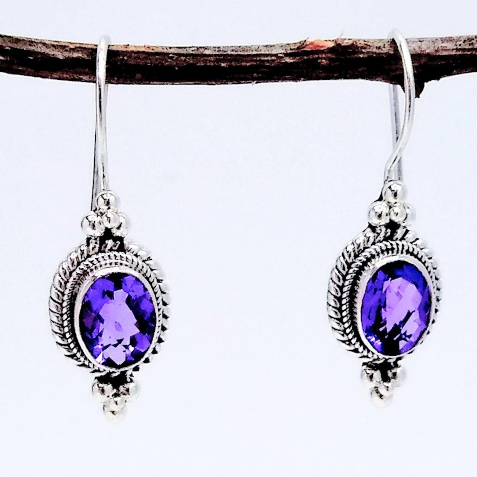 925 Sterling Silver and Amethyst dangle earrings - oval in shape with a double braided settings, and adorned with three stacks spheres both ontop and bottom of the setting, earwires are fixed to earring with a clasp design. February birth stone.