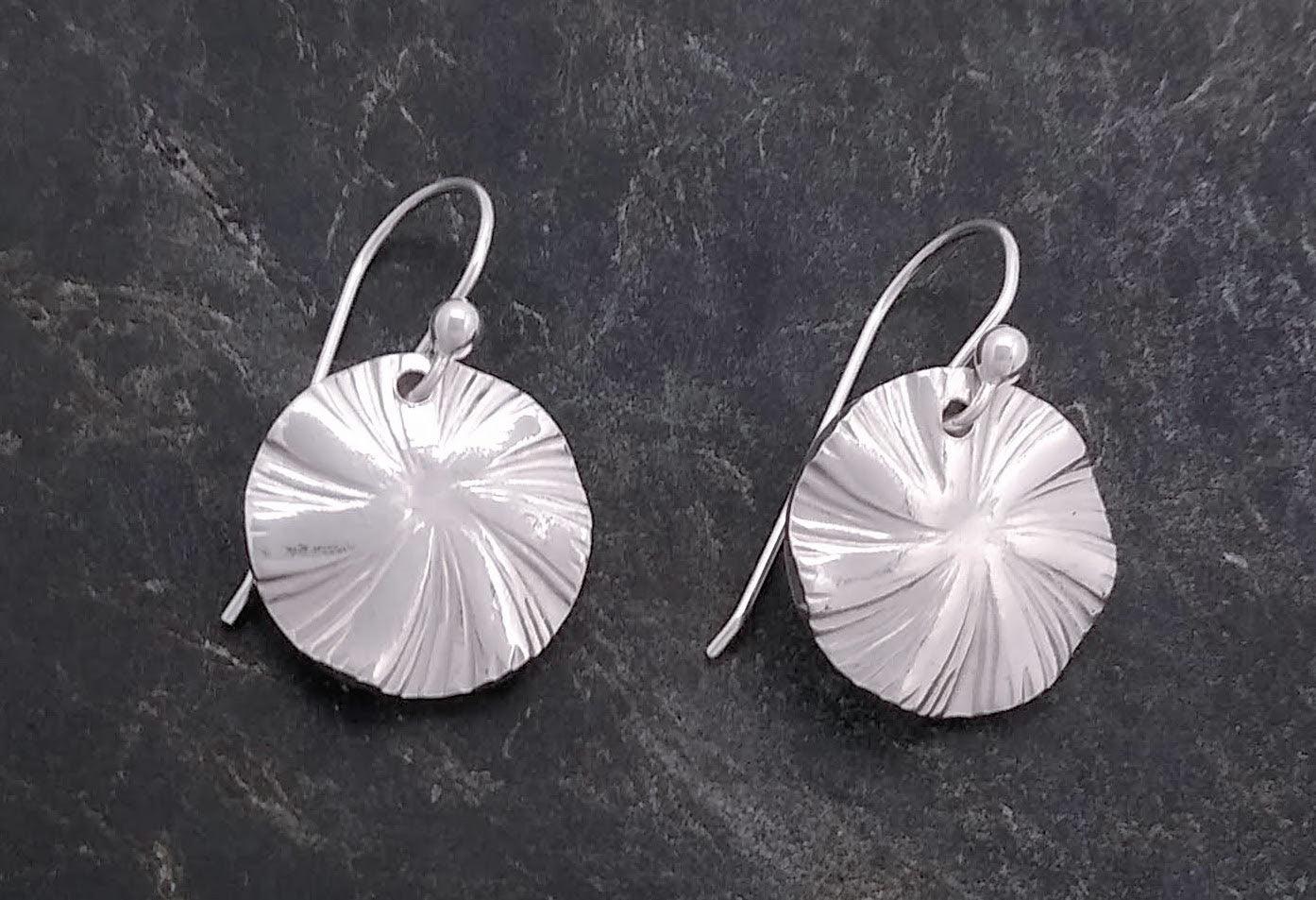 Sterling silver circle drop earrings on a French wire with a swirl stretching out from the middle.