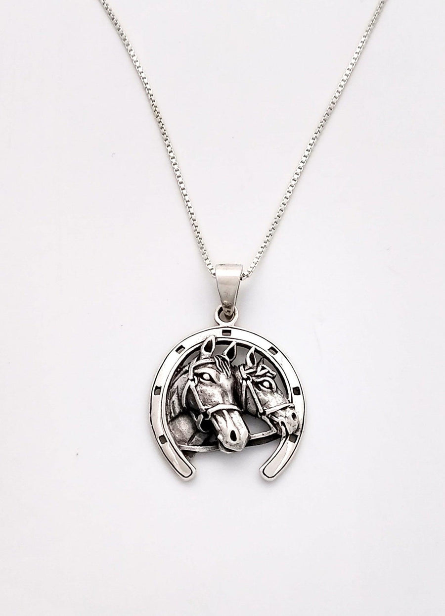 sterling silver pendant with 2 realistic horse faces, surrounded by a border of a horse shoe. 