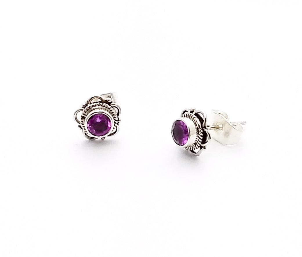 Sterling silver bali-design studs shaped in a floral pattern with an amethyst in the middle. Amethyst is the birthstone for February