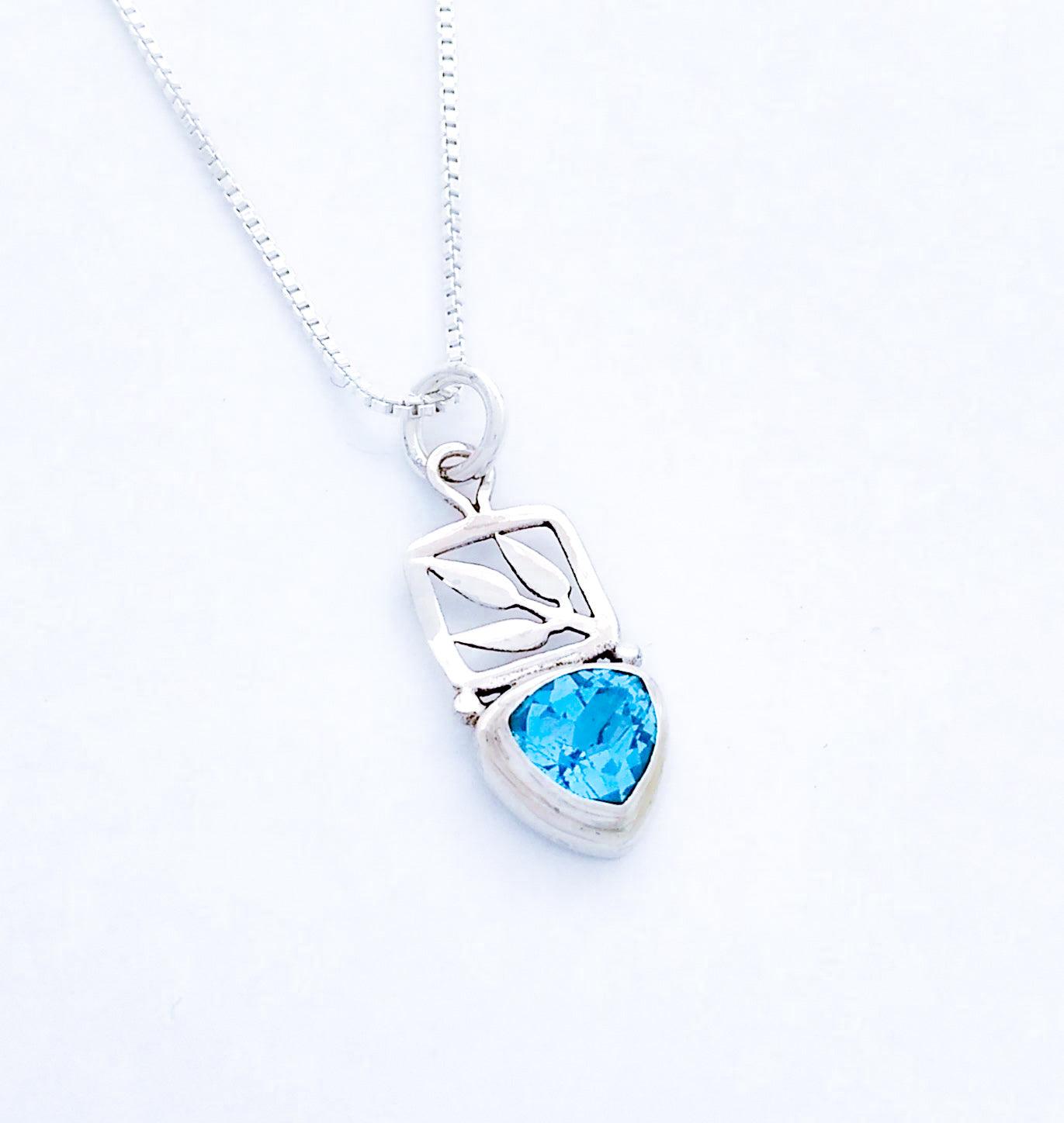 Sterling silver leaf cut out pendant with a small teardrop-shaped blue topaz stone at the bottom