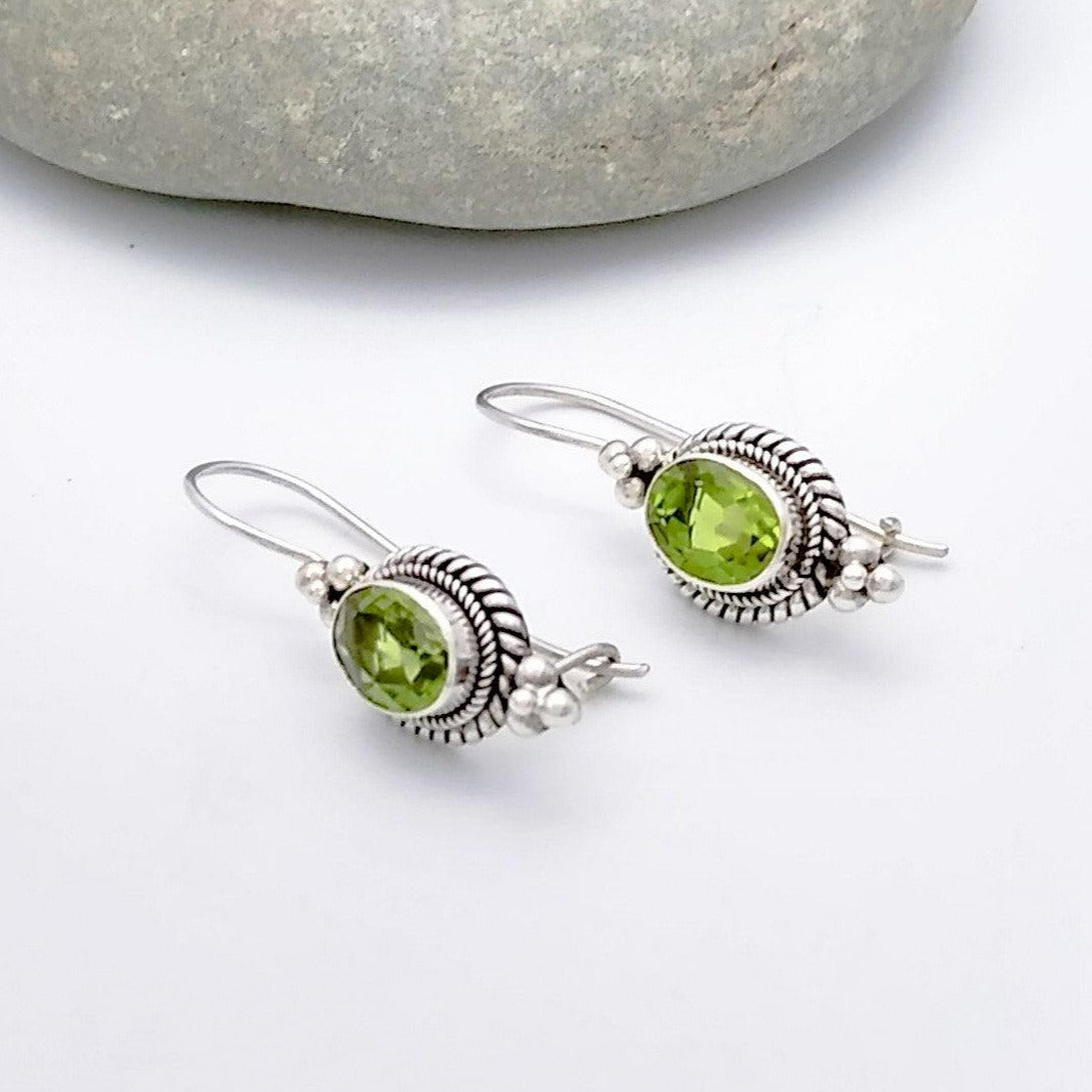 925 Sterling Silver and Peridot dangle earrings - oval in shape with a double braided settings, and adorned with three stacks spheres both ontop and bottom of the setting, earwires are fixed to earring with a clasp design.  August birth stone.