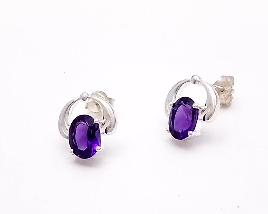 An oval amethyst stud set in sterling with an arch extending over the top to meet the post