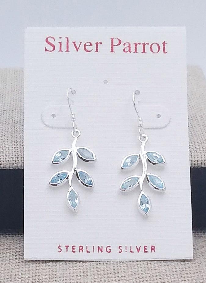 Sterling silver leaf earrings on a French wire. Five blue topaz leaves extend from the center silver branch