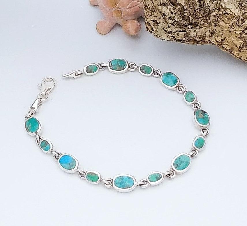 Sterling silver link bracelet with thirteen turquoise stones, going from alternating sizes of big and small stones.
