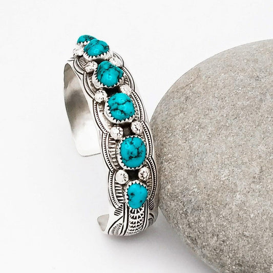 Beautiful hand-made sterling silver cuff bracelet with ornate designs etched into the metal work from which sit six turquoise stones.