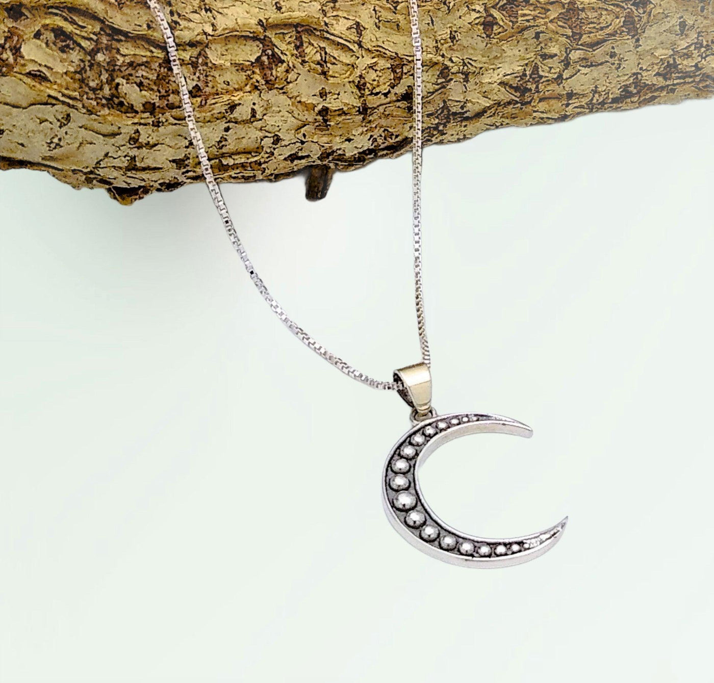 Sterling silver crescent moon pendant with 27 silver balls inlaid in the middle. Comes on an 18-inch chain