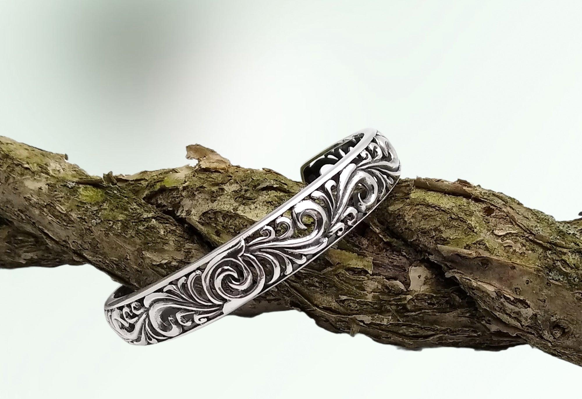 Sterling silver cuff bracelet with ornate curl designs along the metal work.