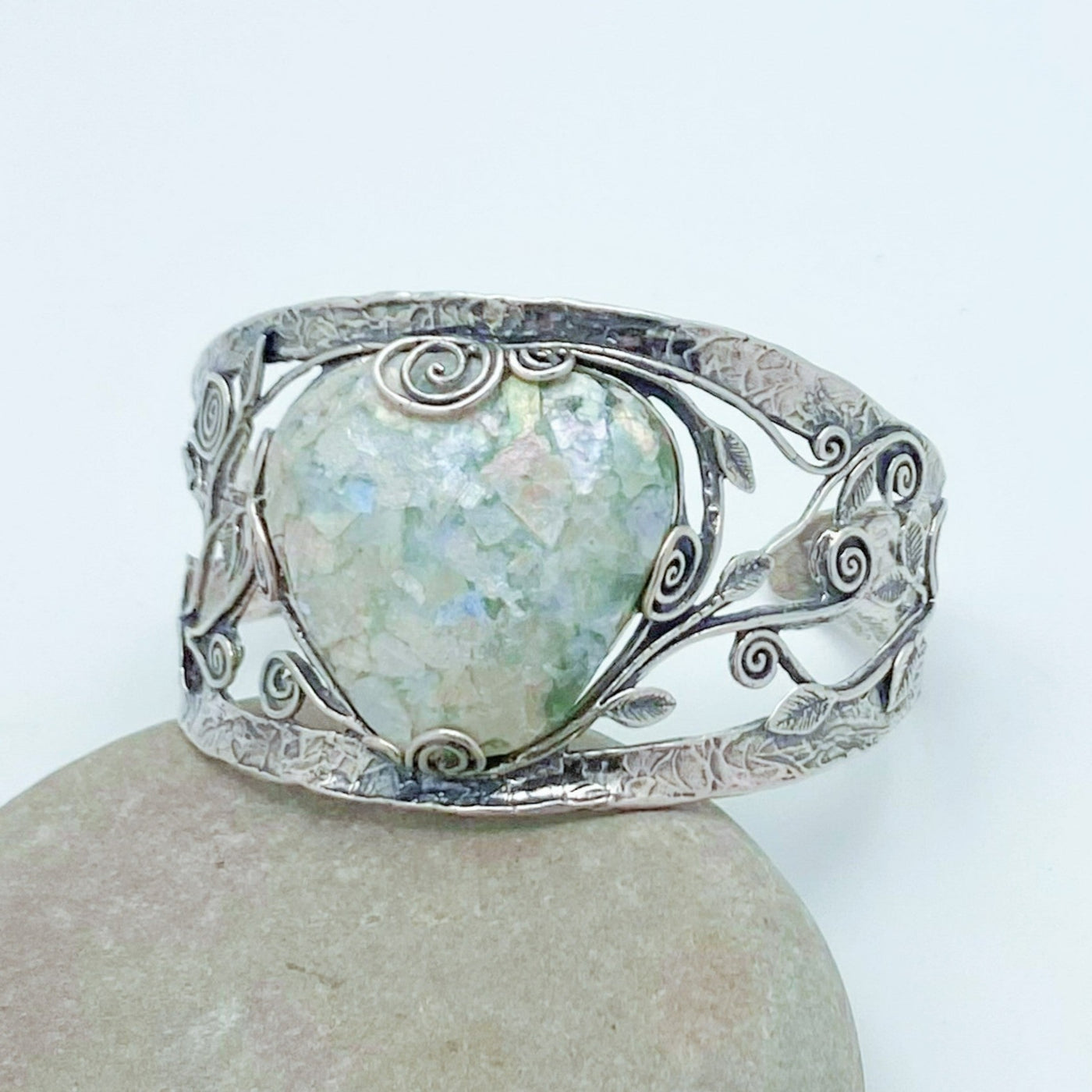 Large triangle shaped piece of Roman Glass set in a 925 Sterling Silver cuff bracelet - The band is adorned with vines and leaves and has a unique hammered appearance.