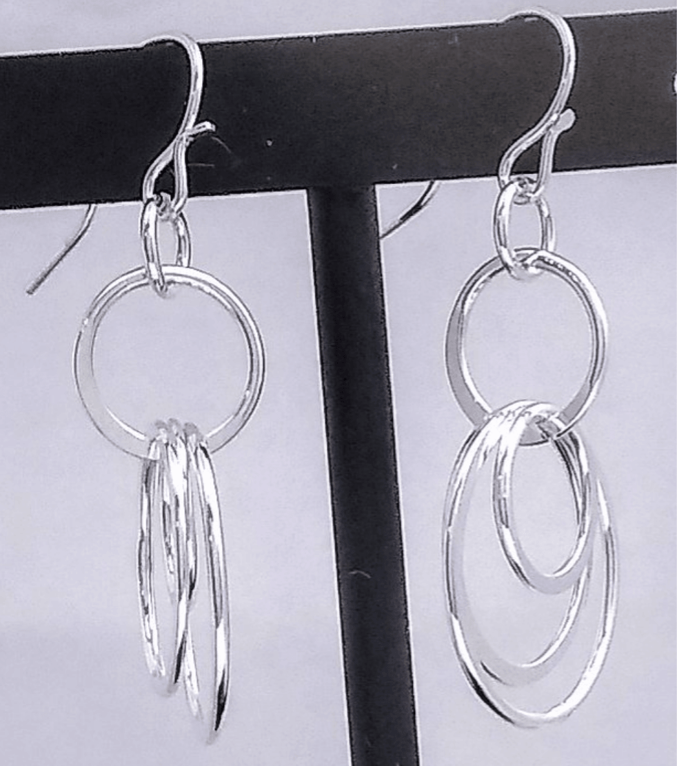 A silver french wire holds a silver hoop with 3 various sized hoops connected to it