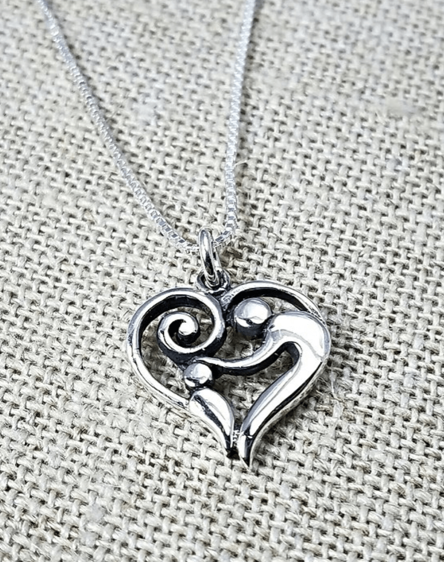 Sterling silver pendant of a heart with an adult patting the head of a child inside.