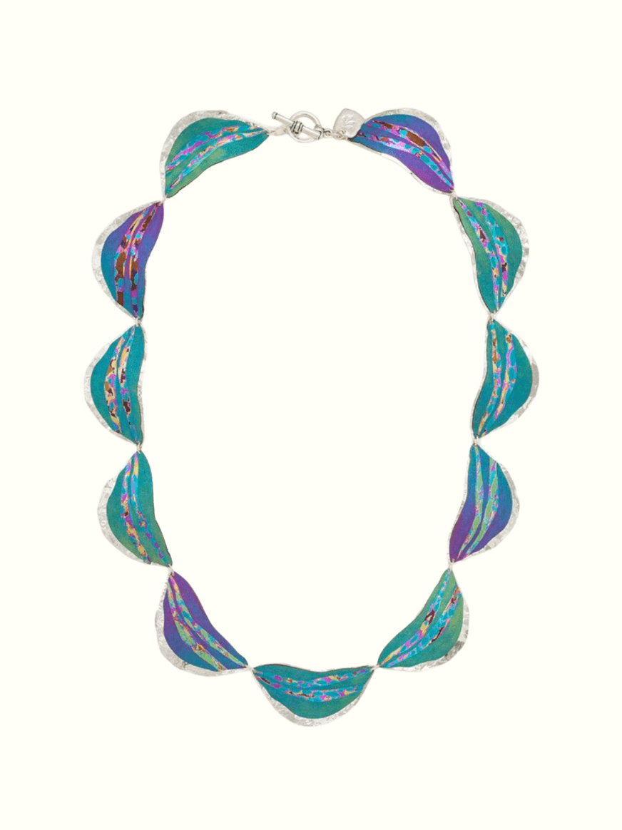 Niobium lunar tides necklace with eleven half-moon shaped wavy tides with varying degrees of purple and green color gradients. Inside each tide is a simple, floral color design in a straight line going across from each side of the tide.