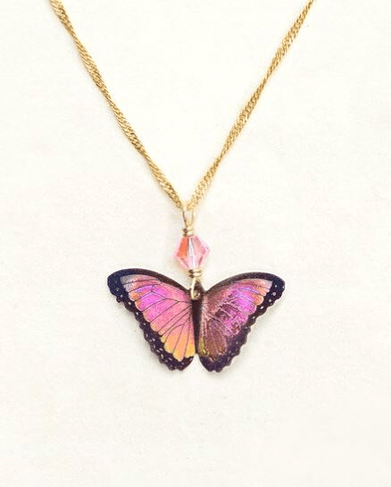 Pink and orange gradient butterfly with black outline on a gold chain with a peach colored bead.