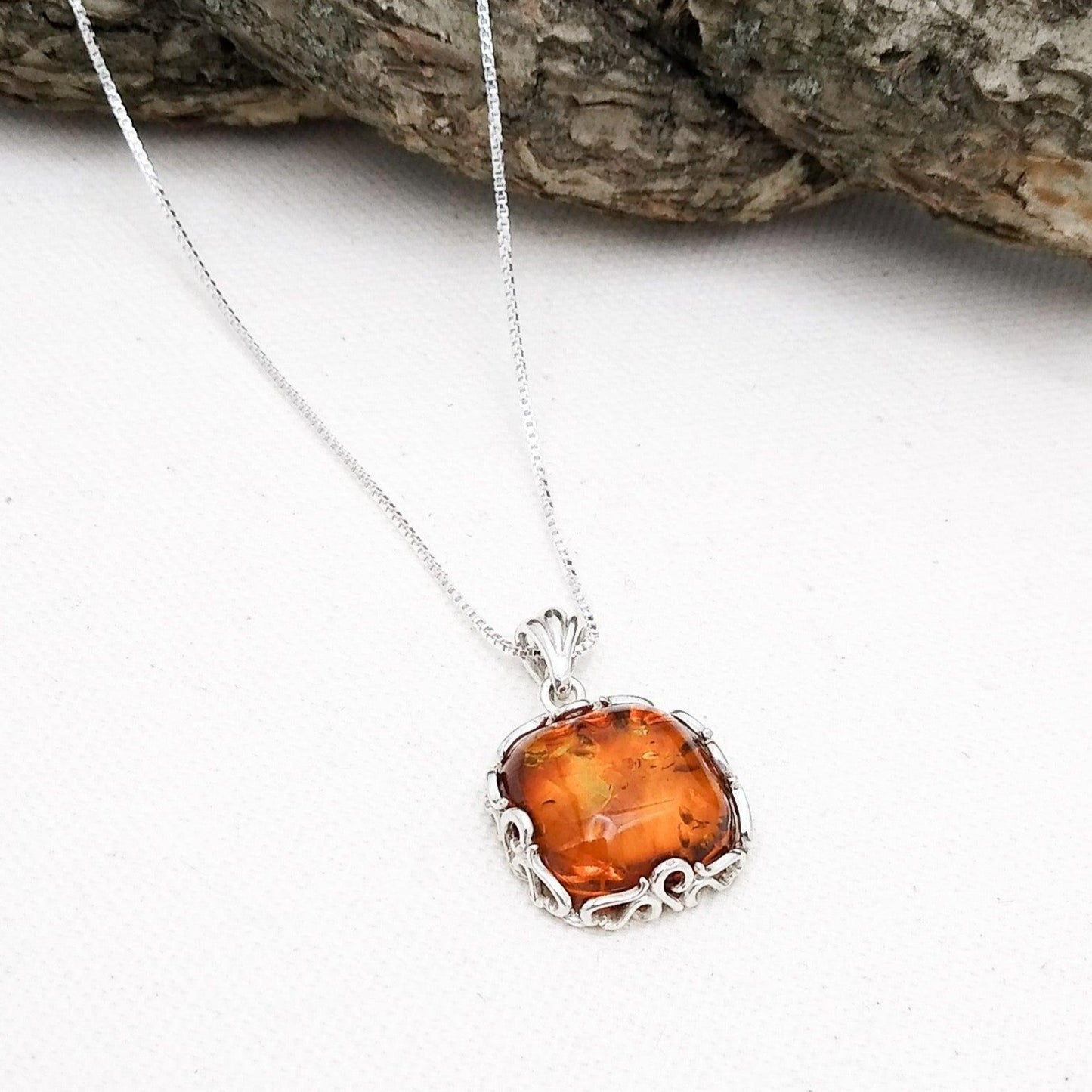 Sterling silver square pendant with an Amber in the middle, surrounded by an ornate sterling border. 18-inch sterling chain