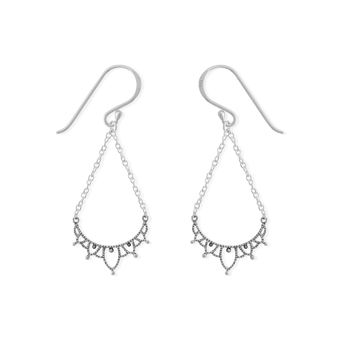Silver filigree earring on white background. Dangles from an ear wire, on two chains, brought together by a filigreed piece of silver.