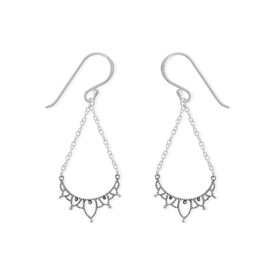 Silver filigree earring on white background. Dangles from an ear wire, on two chains, brought together by a filigreed piece of silver.