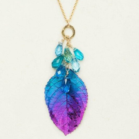 Blue and purple gradient elm leaf necklace with blue dangling beads hanging from a gold-filled chain.