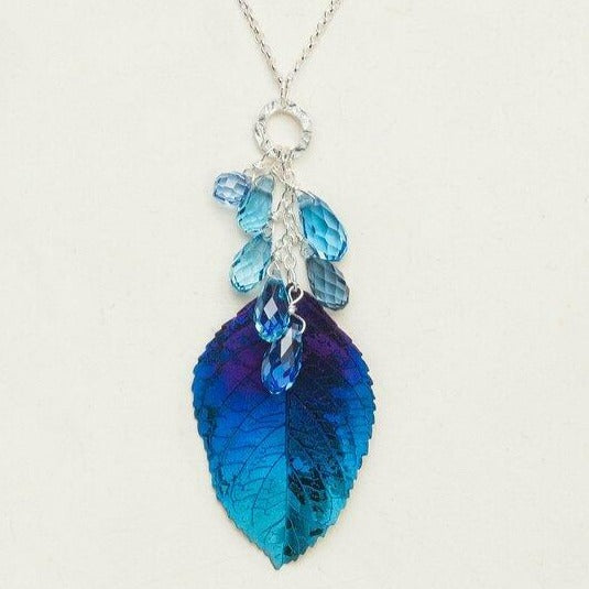 Dark blue to light blue gradient elm leaf necklace with dangling beads hanging from a sterling silver chain.