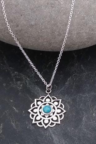 Simple sterling silver floral design with eight pedals with a small circle at the bottom stretching out from a small, blue Turquoise stone sitting in the middle. Floral design is surrounded by a simple geometric curve between each pedal. Comes with adjustable silver box chain.