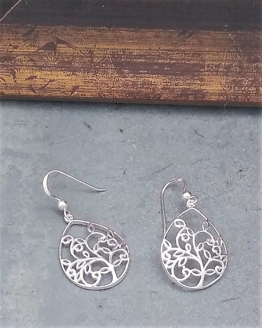 Lightweight simple sterling silver teardrop-shaped earrings with a hollow tree design in the metal. On a French wire