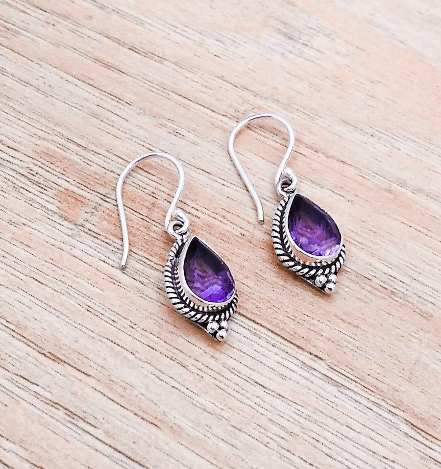 Amethyst teardrop dangle earrings 1.5 inches long including the wire. The stones are nicely faceted and a darker purple.  Made in Bali the bezels are intricate wire work.