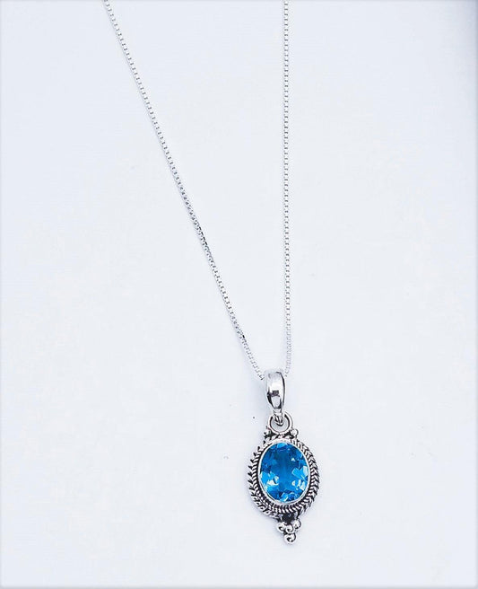 Sterling silver pendant with woven rope design along the sides, with three small silver balls at the top arranged in a triangular fashion. In the middle is a blue topaz stone. Comes on an 18-inch chain. December birthstone