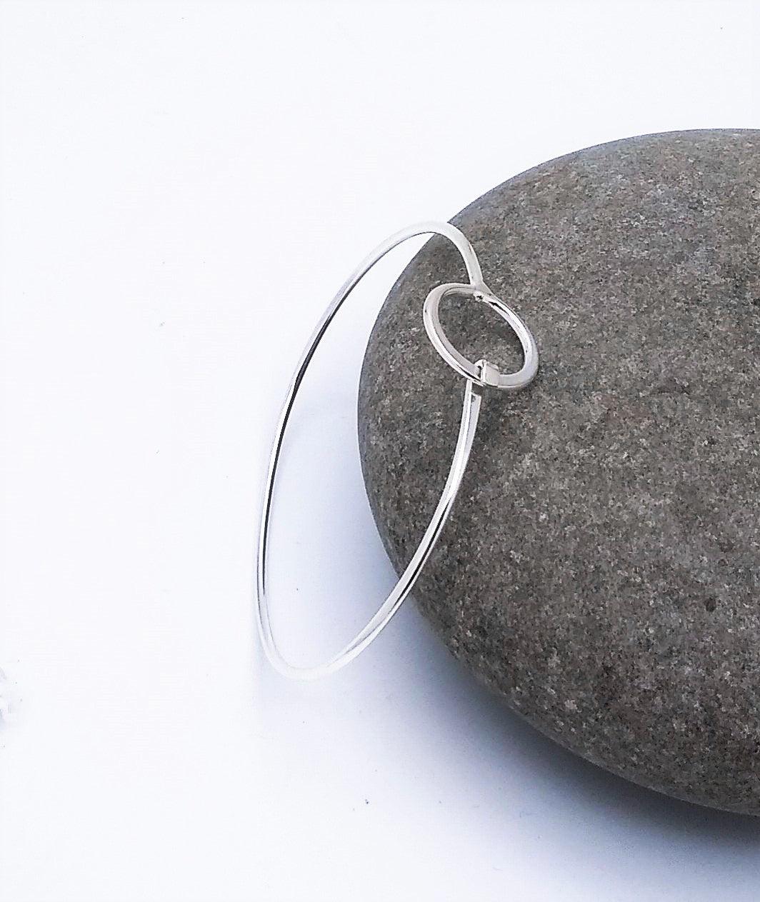 Thin sterling silver bracelet with a circle at the top that clasps.