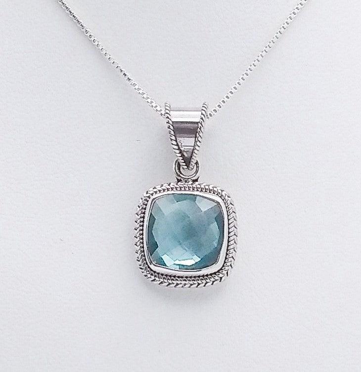 Sterling silver square-shaped pendant with blue topaz in the middle, bordered by an ornate rope design. 18-inch sterling chain. December birthstone