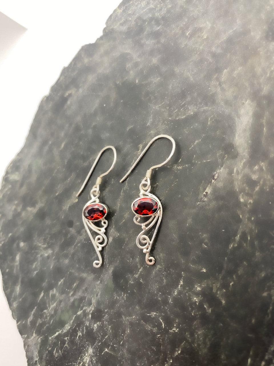 Sterling silver drop earrings on a French wire with an Garnet stone at the top and filigree design at the bottom.
